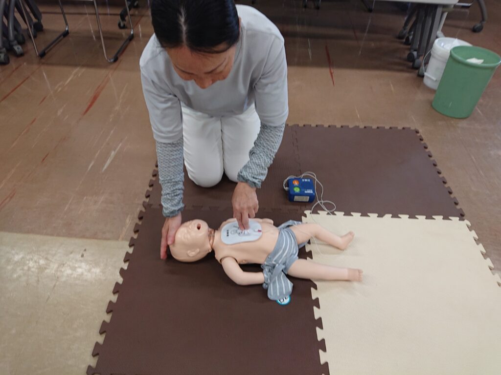 乳児の人形にAEDパッドを装着し、救命処置を訓練するタイムカプセル保育園の職員。
