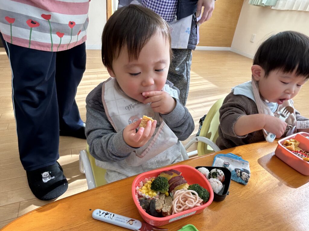 タイムカプセル保育園のお弁当の時間に、彩り豊かな手作りお弁当を小さな手で掴んで、夢中でパクパク食べる男の子