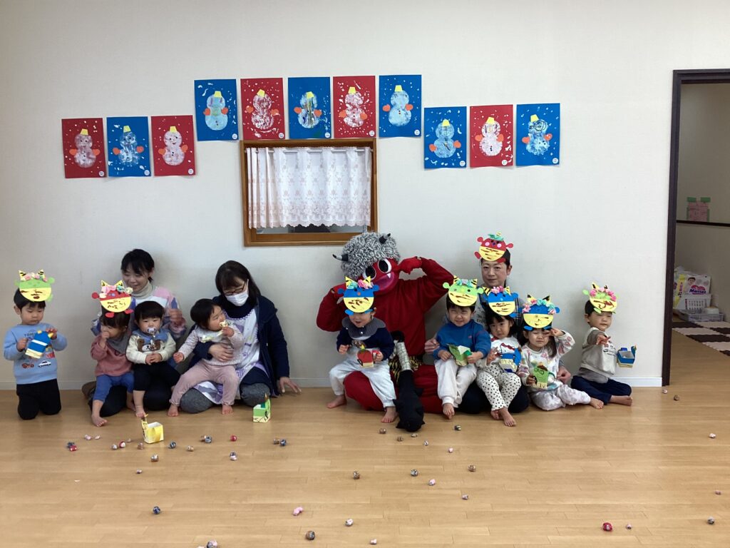 兵庫県丹波市氷上のリトルわんぱく保育園での節分会。赤鬼を囲んで手作りお面をつけた子どもたちと先生の集合写真