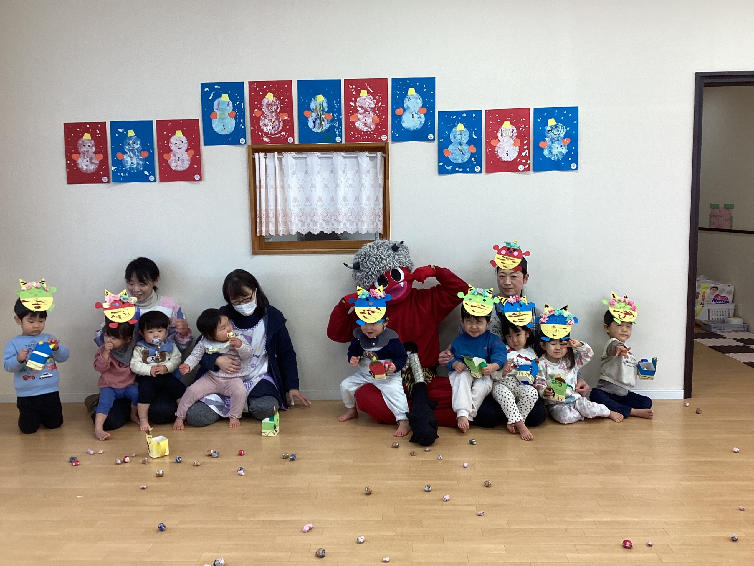 兵庫県丹波市氷上のリトルわんぱく保育園での節分会。赤鬼を囲んで手作りお面をつけた子どもたちと先生の集合写真