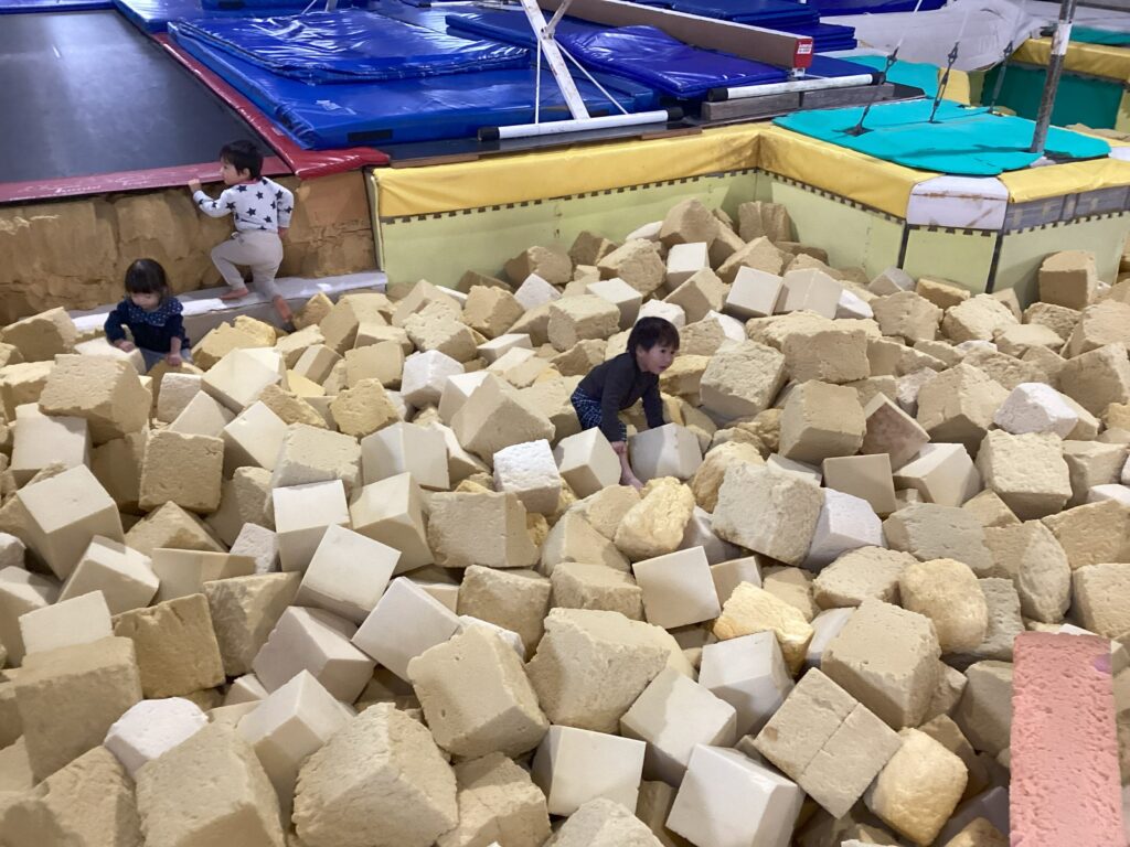 タイムカプセル保育園の体操あそび。体育館の巨大なスポンジプールに潜り込んで夢中で遊ぶ0・1歳児クラスの子ども