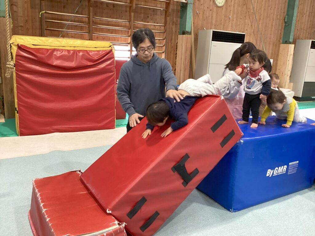 タイムカプセル保育園の体操あそび。専門の体操コーチによる安全なサポートでマット運動を楽しむ子どもたち